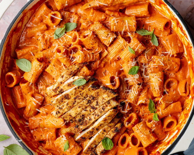 Spicy vodka pasta in skillet with grilled chicken.
