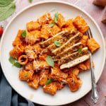 Spicy voda pasta with chicken on white plate with fork.