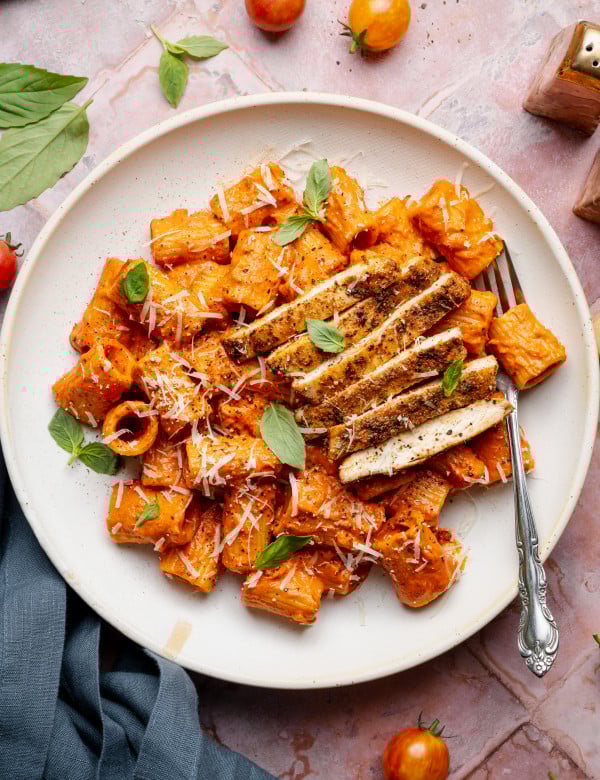 Spicy voda pasta with chicken on white plate with fork.