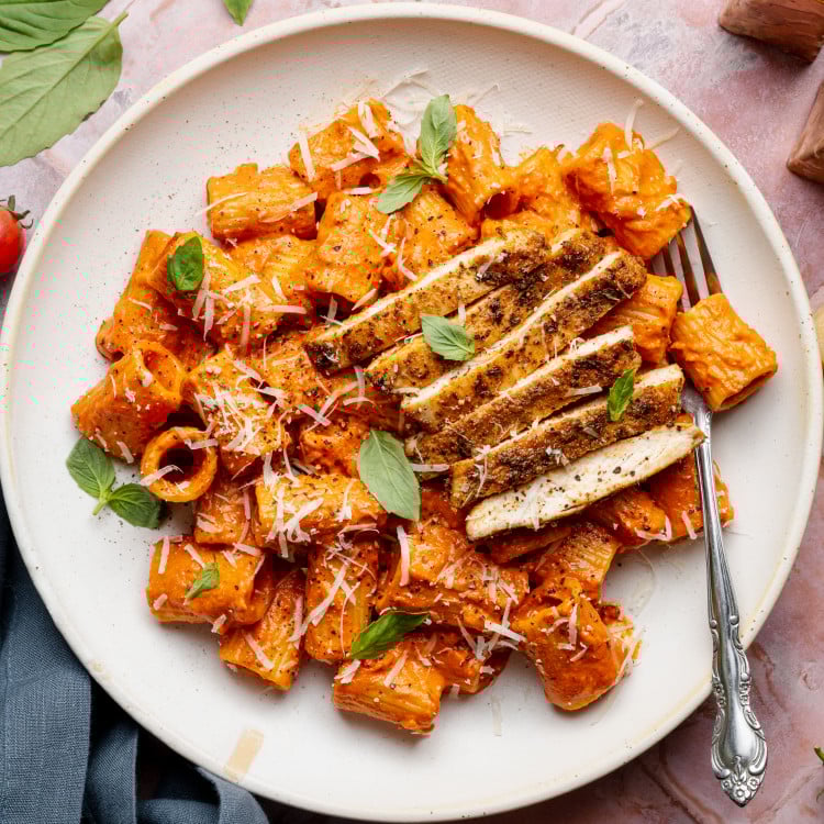 Spicy voda pasta with chicken on white plate with fork.
