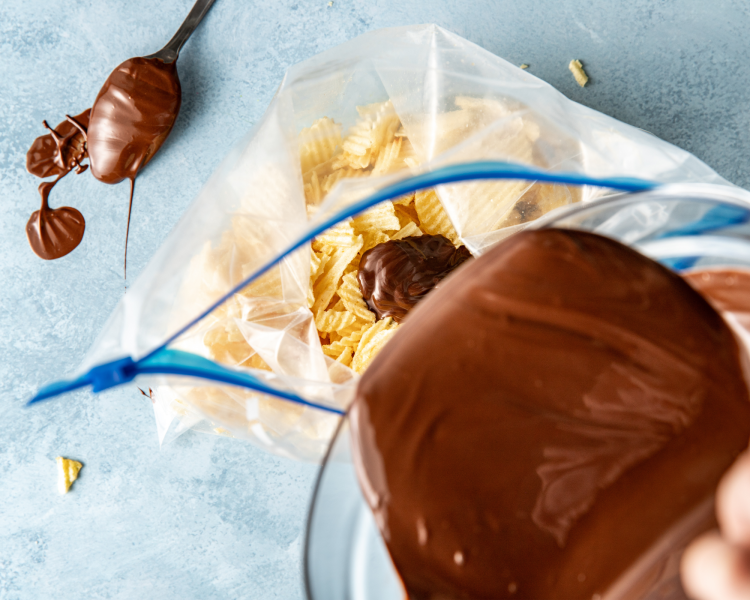 Pouring melted chocolate into zip lock bag with crushed potato chips.