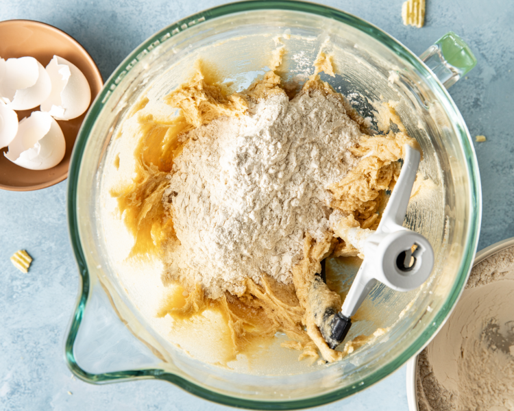 Adding dry ingredients to wet ingredients in glass mixing bowl.