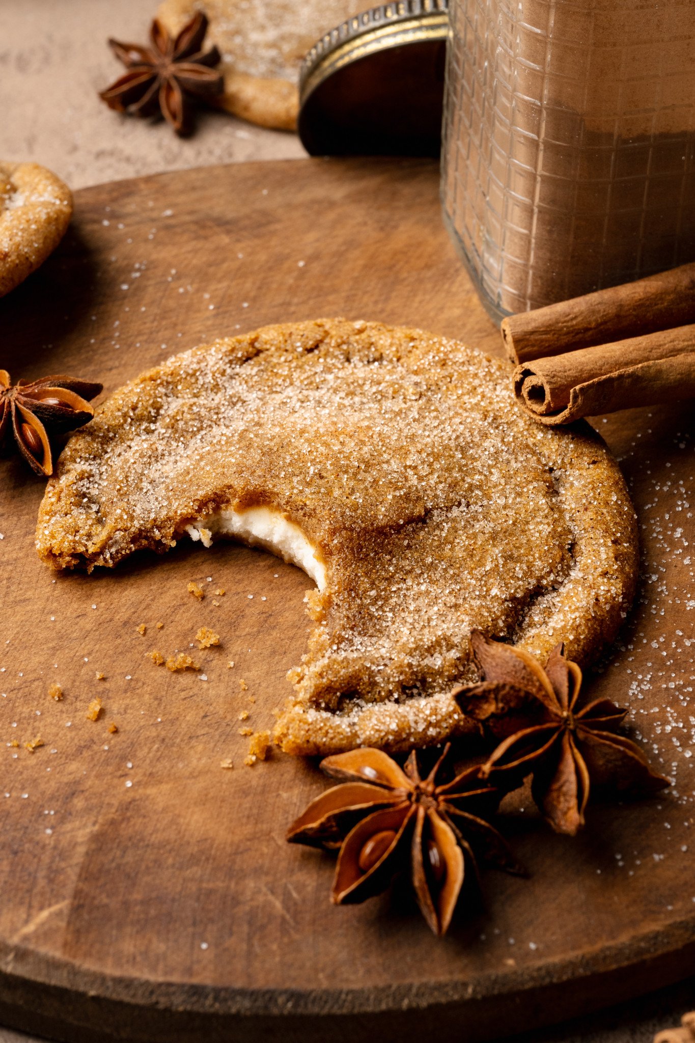 Pumpkin cheesecake cookie with bite taken out of the center on wood cutting board.