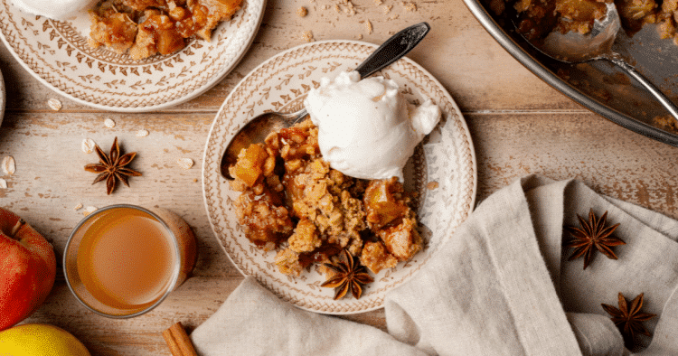 Apple crisp served on plate with ice cream and spoon.