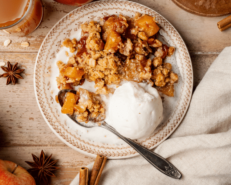 Appel crisp served with vanilla ice cream on plate with spoon.
