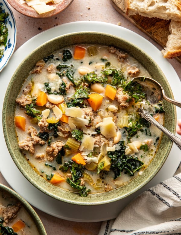 Sausage and kale soup in bowl with spoon.
