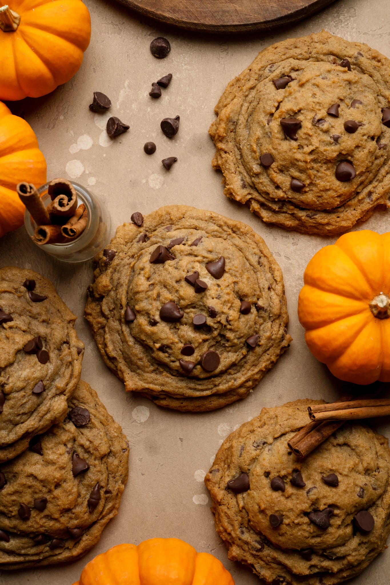 Pumpkin chocolate chip cookies topped with extra chocolate chips on parchment paper.
