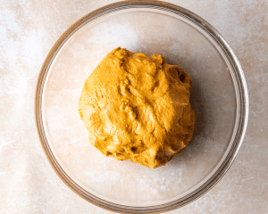 Pumpkin cinnamon roll dough in greased bowl.