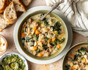 Sausage, kale, and bean soup in a green bowl with a spoon.