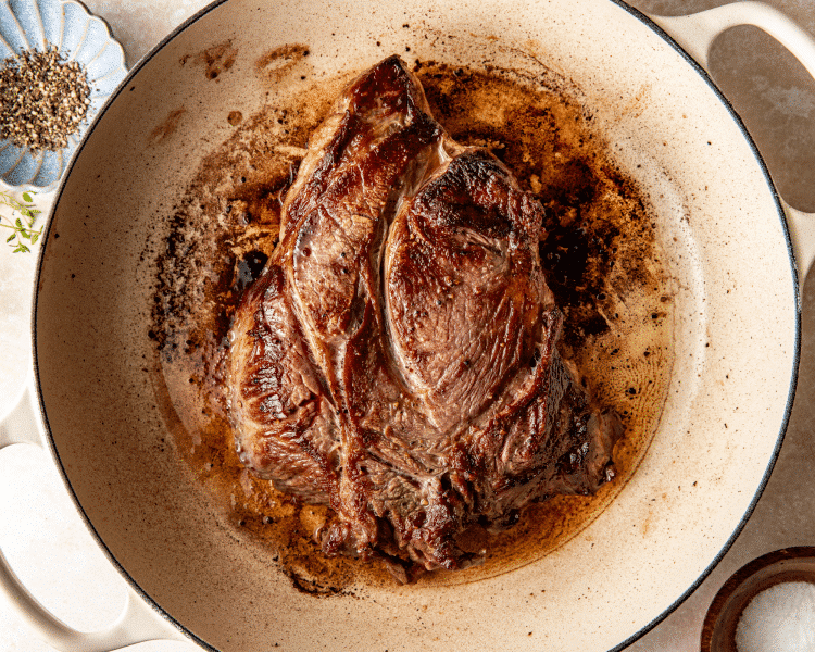 Chuck roast seared on both sides in a large skillet.