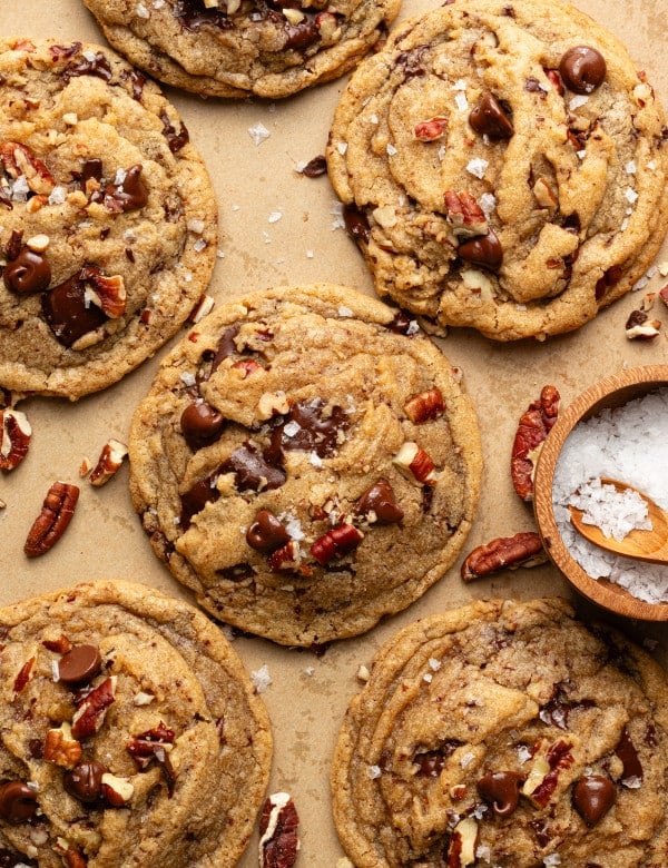 Brown butter pecan chocolate chip cookies baked and topped with extra pecans and flaky sea salt.