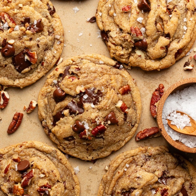 Brown butter pecan chocolate chip cookies baked and topped with extra pecans and flaky sea salt.