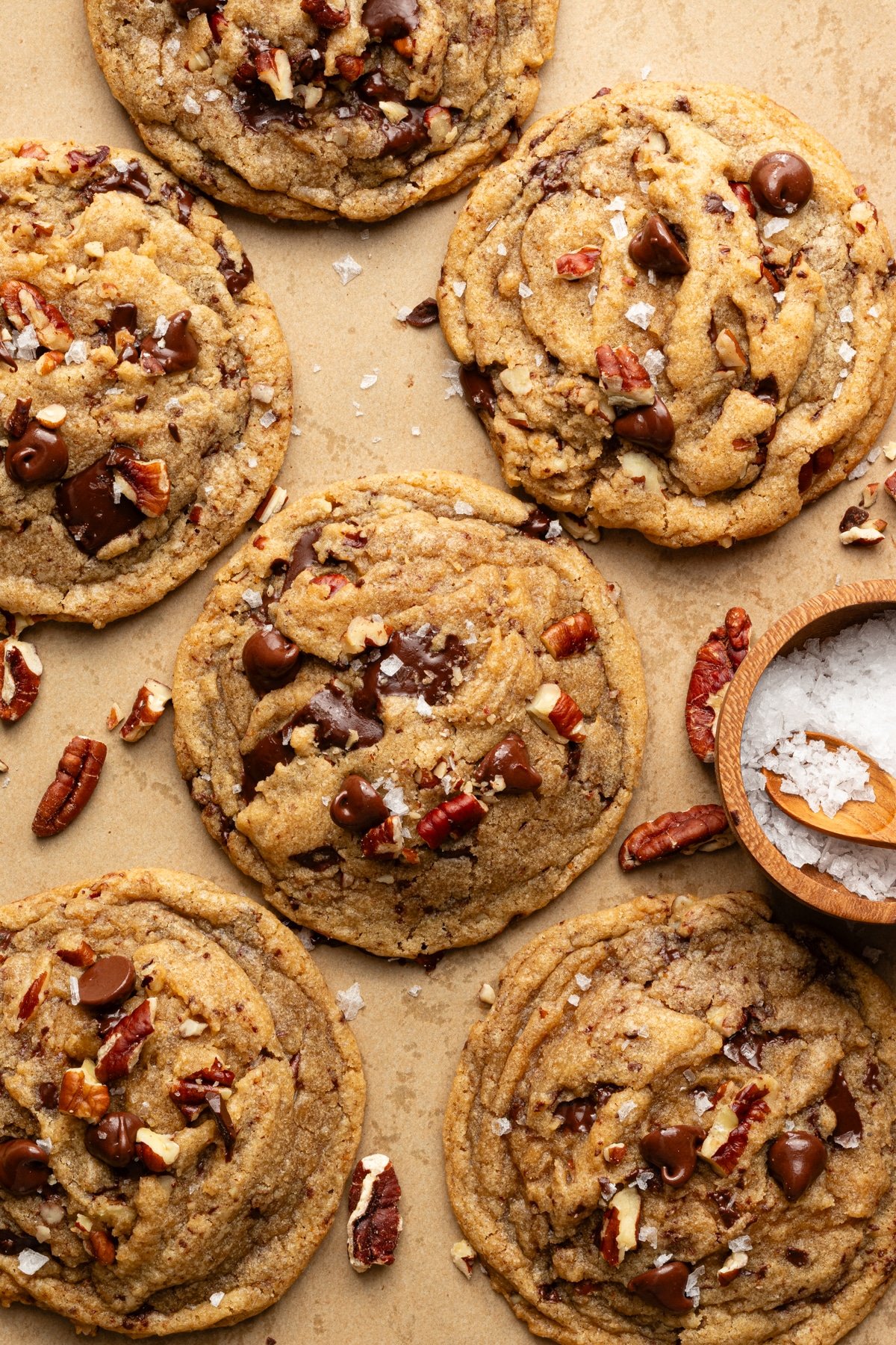 Brown butter pecan chocolate chip cookies baked and topped with extra pecans and flaky sea salt.