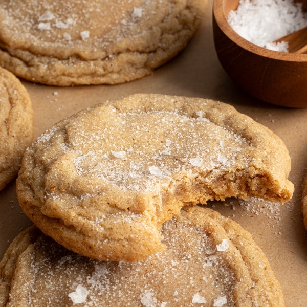 Bite taken out of brown sugar cookie on parchment paper.