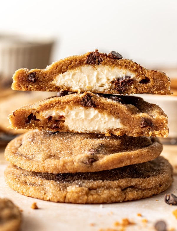 Biscoff cheesecake cookies stacked on top of each other with top cookie broken in half to show cheesecake center.