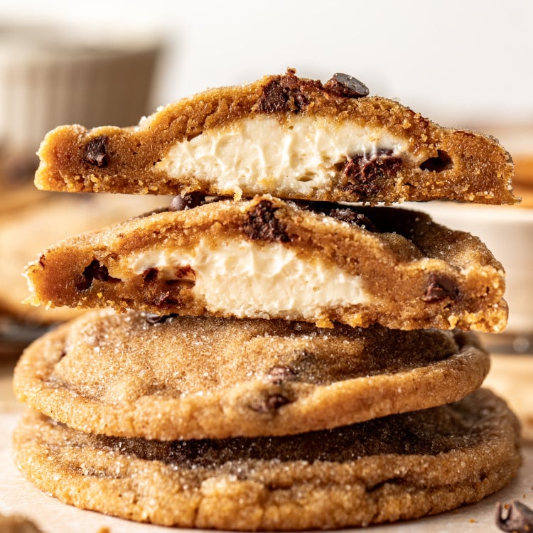 Biscoff cheesecake cookies stacked on top of each other with top cookie broken in half to show cheesecake center.