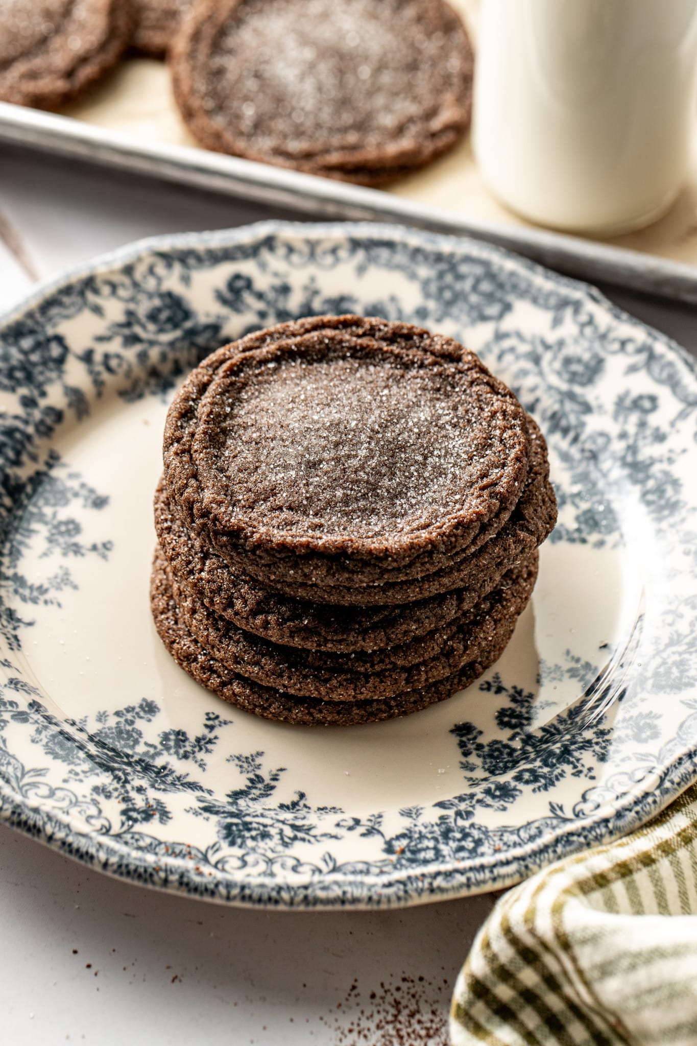 Chewy chocolate chip cookies stacked on top of each other on blue floral plate.