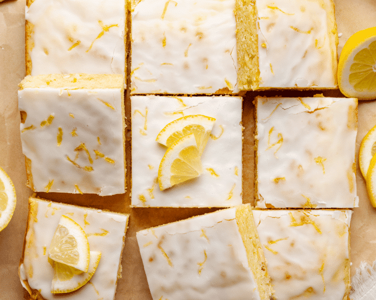 Lemon brownies garnished with lemon zest and lemon wedges cut into 9 squares.