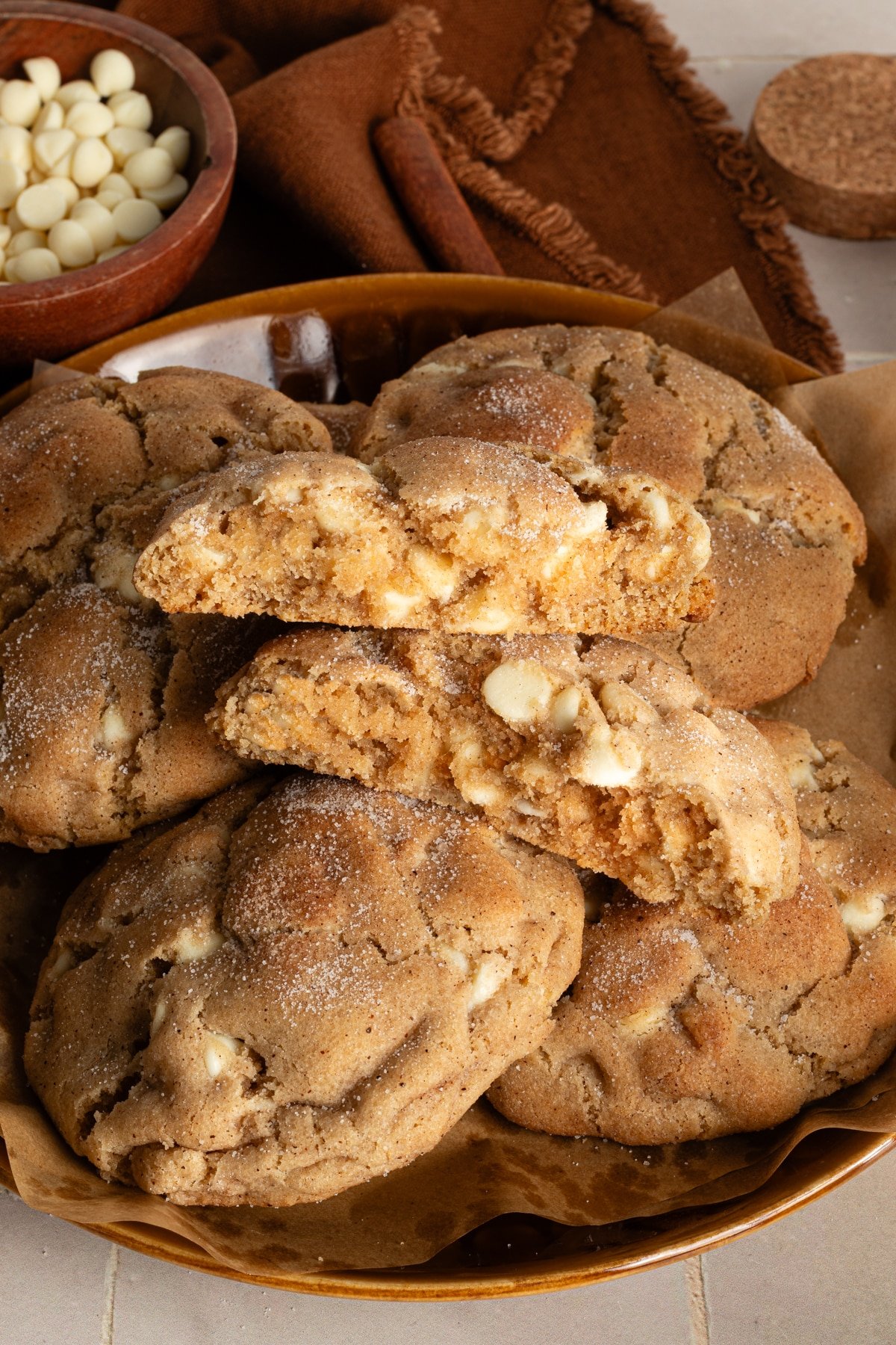 Snickerdoodle cookie broken in half on top of other cookies in bowl.
