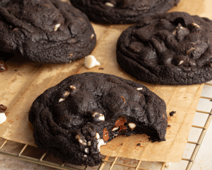 Bite taken out of black and white cookie on wire rack.
