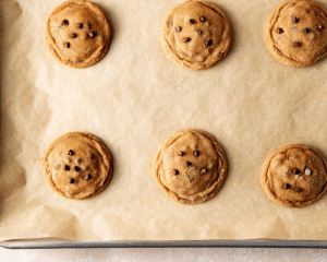 Six cheesecake biscoff cookies baked on baking sheet and sprinkled with extra granulated sugar.
