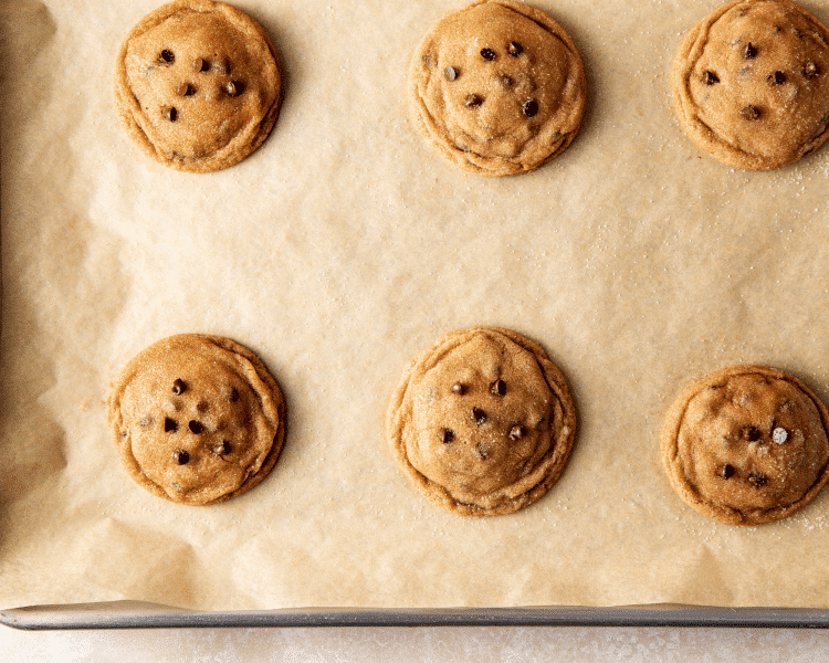 Six cheesecake biscoff cookies baked on baking sheet and sprinkled with extra granulated sugar.