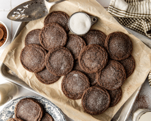 Chocolate cookies on parchment lined baking sheet sprinkled with extra sugar.