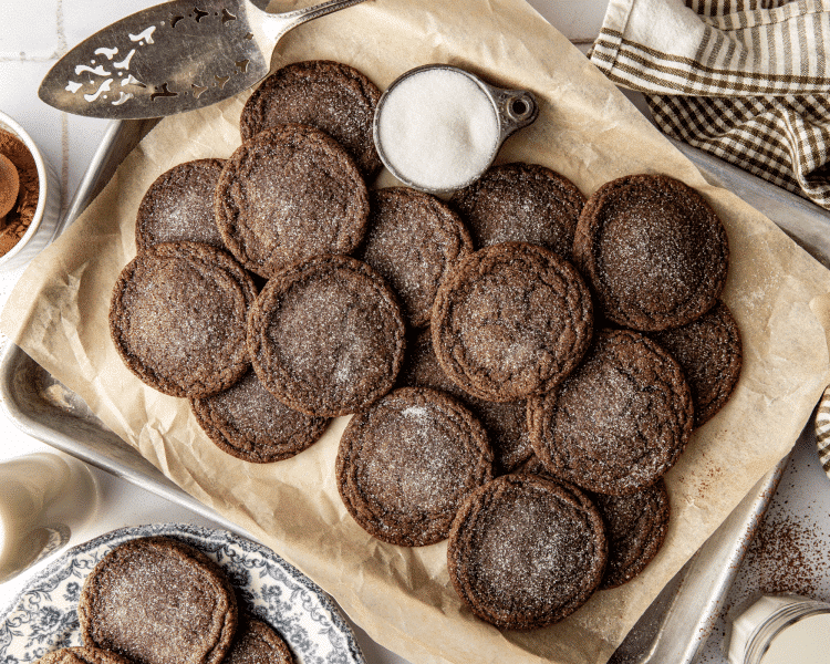 Chocolate cookies on parchment lined baking sheet sprinkled with extra sugar.