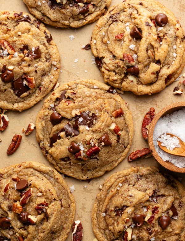 Brown butter pecan chocolate chip cookies baked and topped with extra pecans and flaky sea salt.