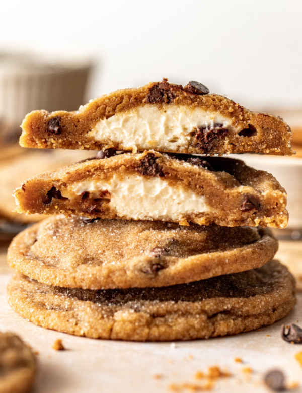 Biscoff cheesecake cookies stacked on top of each other with top cookie broken in half to show cheesecake center.