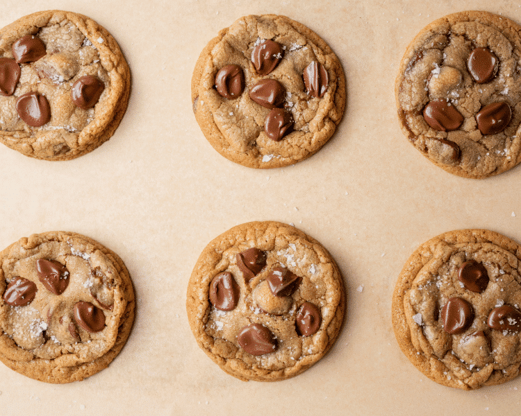 Nutella chocolate chip cookies baked on parchment-lined baking sheet and sprinkled with flaky sea salt after baking.