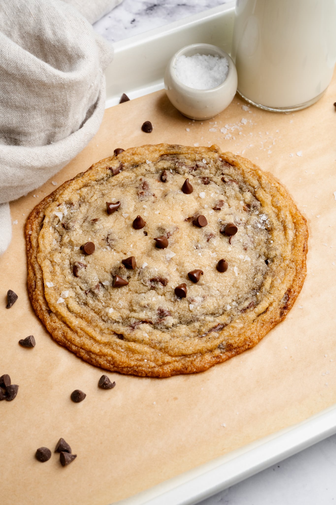 Giant single-serve thin and chewy cookie on baking tray lined with parchment paper.