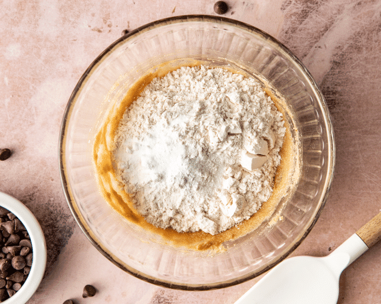 Flour sprinkled over sugars and butter in mixing bowl.