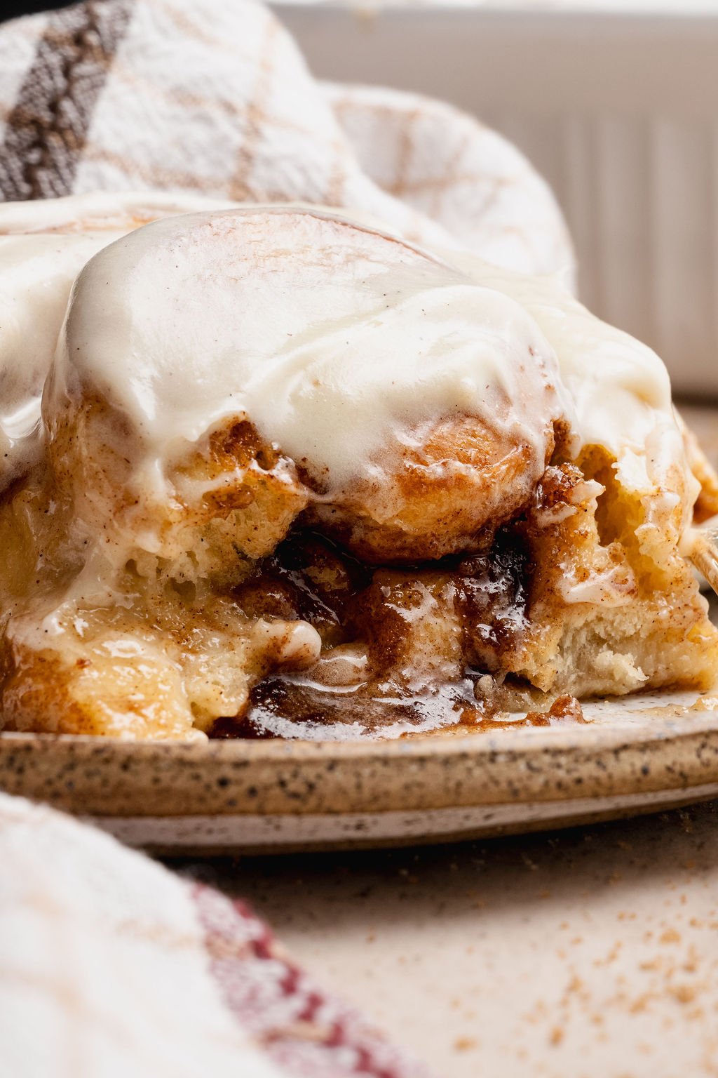Macro shot of a gooey cinnamon roll center covered in creamy frosting, highlighting the texture of the fluffy dough and caramelized cinnamon filling.