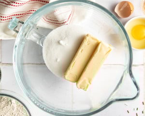 Butter and granulated sugar in a large glass mixing bowl, ready to be creamed together for Christmas sprinkle sugar cookies.