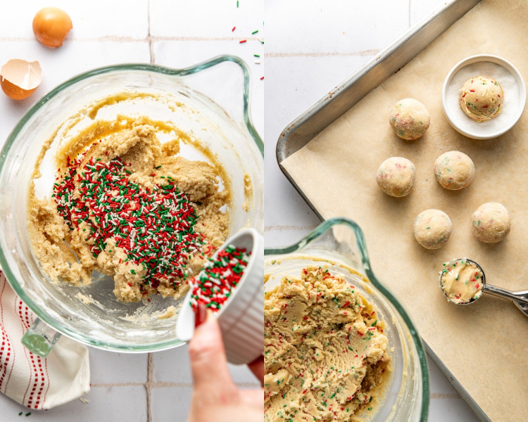 Mixing bowl filled with sprinkle sugar cookie dough as red and green sprinkles are poured in and folded with a spatula, then scooped into dough balls on a parchment-lined baking sheet.