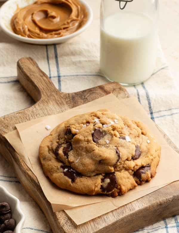 Giant peanut butter chocolate chip cookie on wooden serving platter.