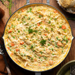 Chicken pot pie orzo cooked in a deep skillet and garnished with fresh parsley.