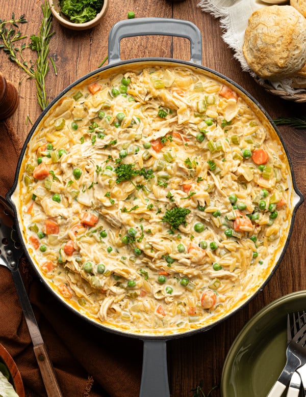 Chicken pot pie orzo cooked in a deep skillet and garnished with fresh parsley.