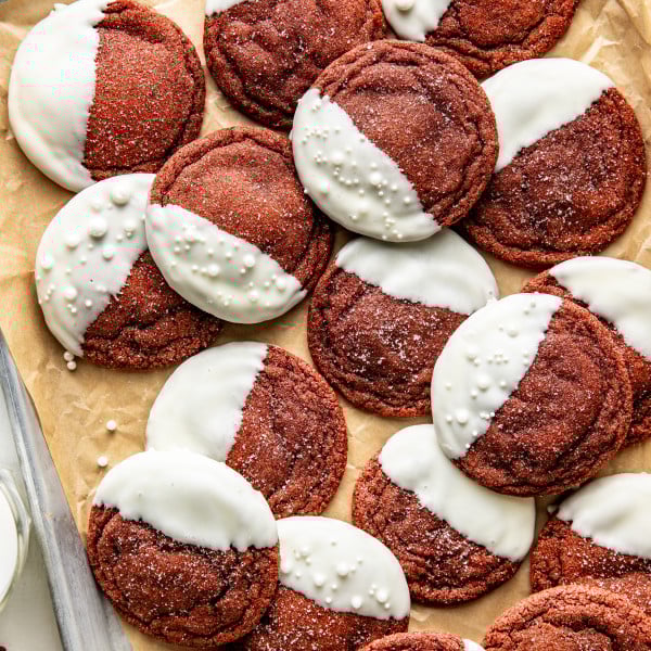 White chocolate dipped red velvet cookies on parchment-lined baking tray.