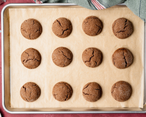 Chocolate peanut butter cookies baked on parchment-lined tray before adding Hershey kisses.