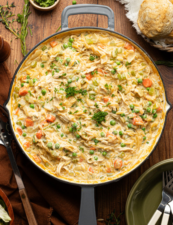 Chicken pot pie orzo cooked in a deep skillet and garnished with fresh parsley.