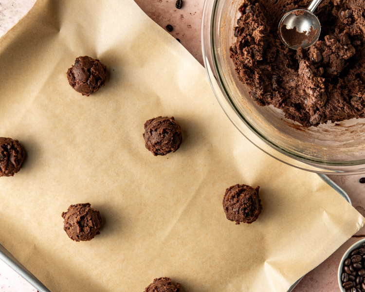 Scooping the cookie dough into 2.5 tablespoons and placing the balls on a parchment-lined baking tray.