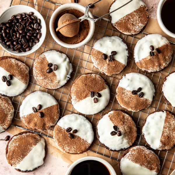 Garnishing the espresso martini cookies with cocoa powder and coffee beans on wire rack.