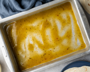 Spreading a thin layer of enchilada sauce on the bottom of a 9x13 pan before adding enchiladas.
