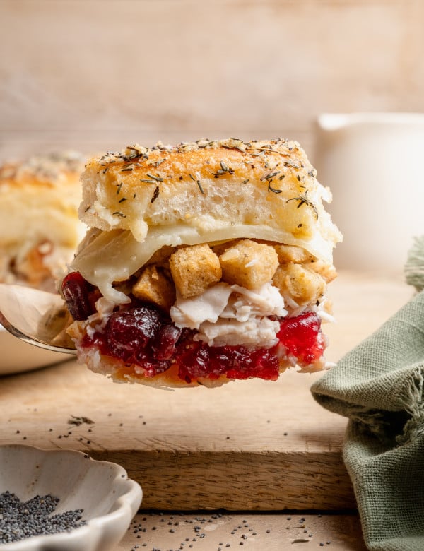 Fork holding up one thanksgiving leftover slider so you can see the different layers.