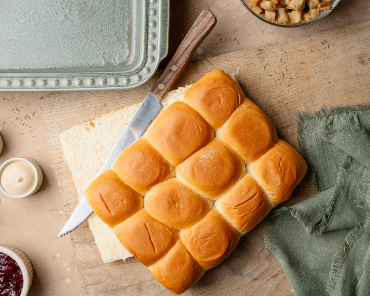 Slicing hawaiian rolls in half.