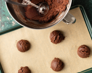 Scooping cookie dough onto prepared baking sheet.