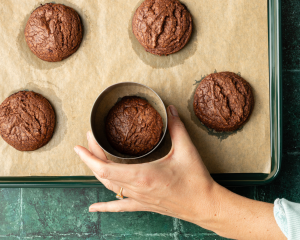 Using a circular cookie cutting to cookie-scoot cookies after taking them out of the oven.