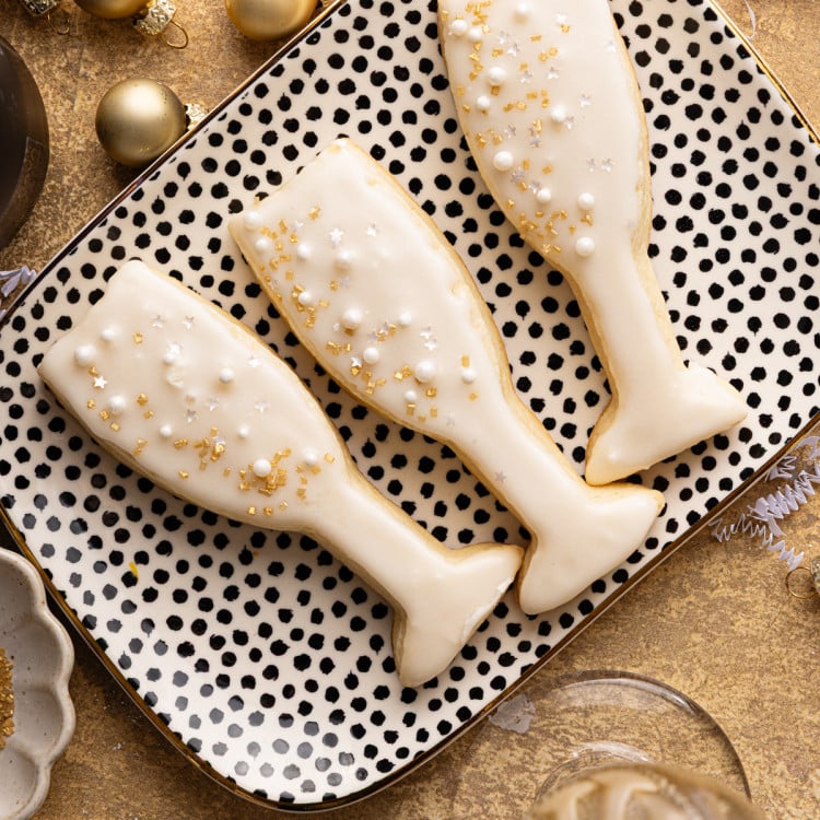 Three sparkling champagne cookies on white and black dotted serving tray.